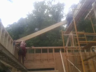 Carpenter raising a rafter beam on a new second story frame in Upper Darby