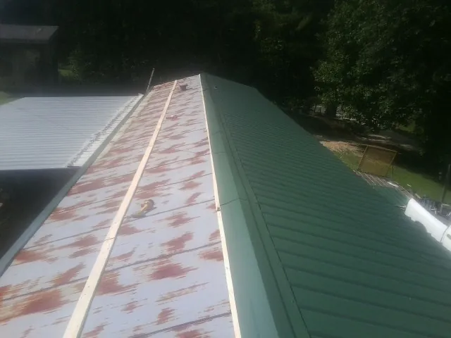 Old rusted panels beside newly installed green metal roofing — Wind Damage Roof Repair by Roofing Brothers in Upper Darby