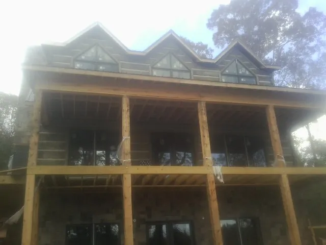 Dormers and porch framing on a large log home under construction — Roof Coating work by our crew in Upper Darby