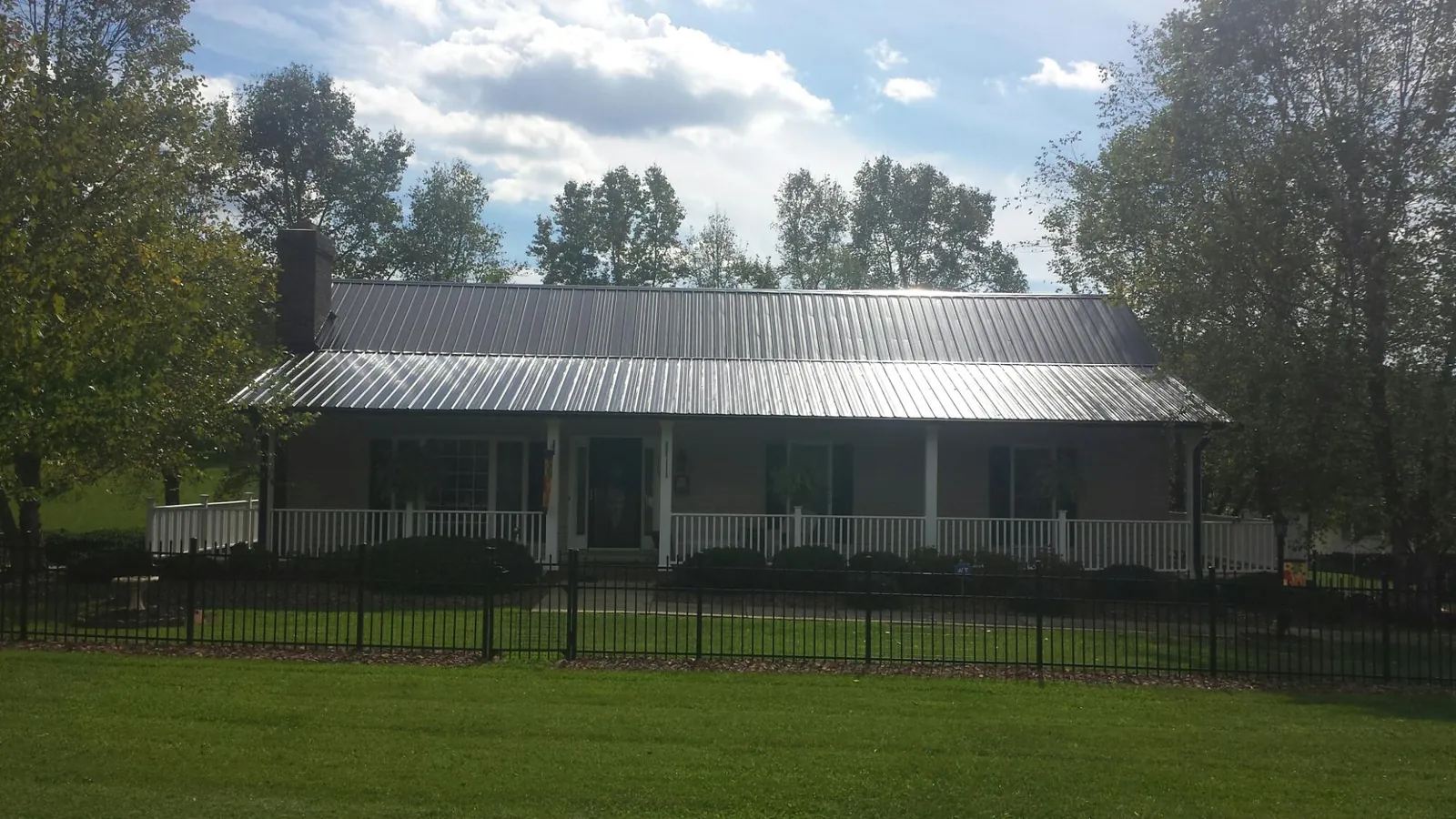 Gray metal roof on a brick ranch with a full width front porch — Gutter Guard Installation work by our crew in Upper Darby