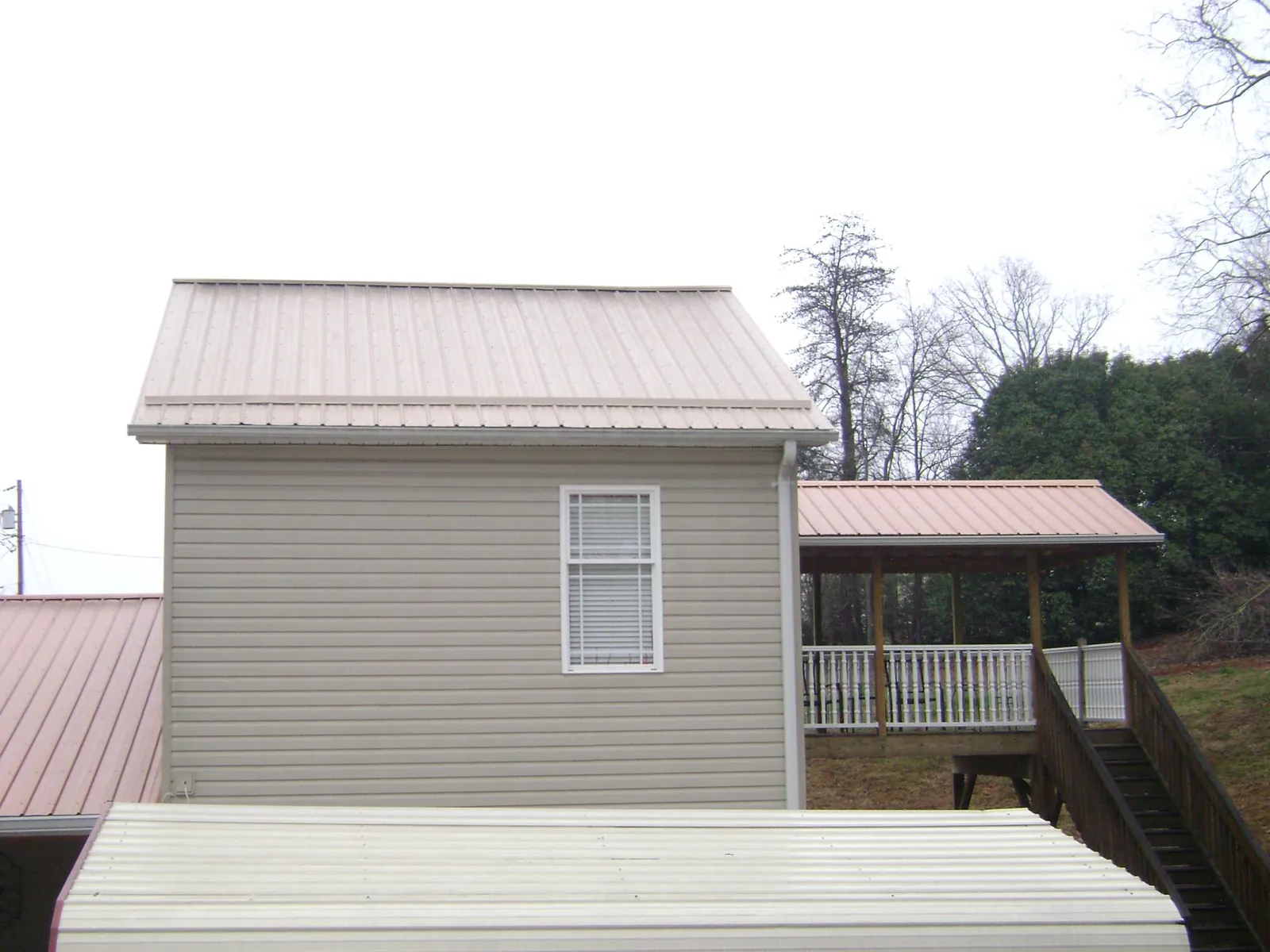 Tan metal roofs on a two story addition and attached porch, from a Roof Replacement job in Upper Darby