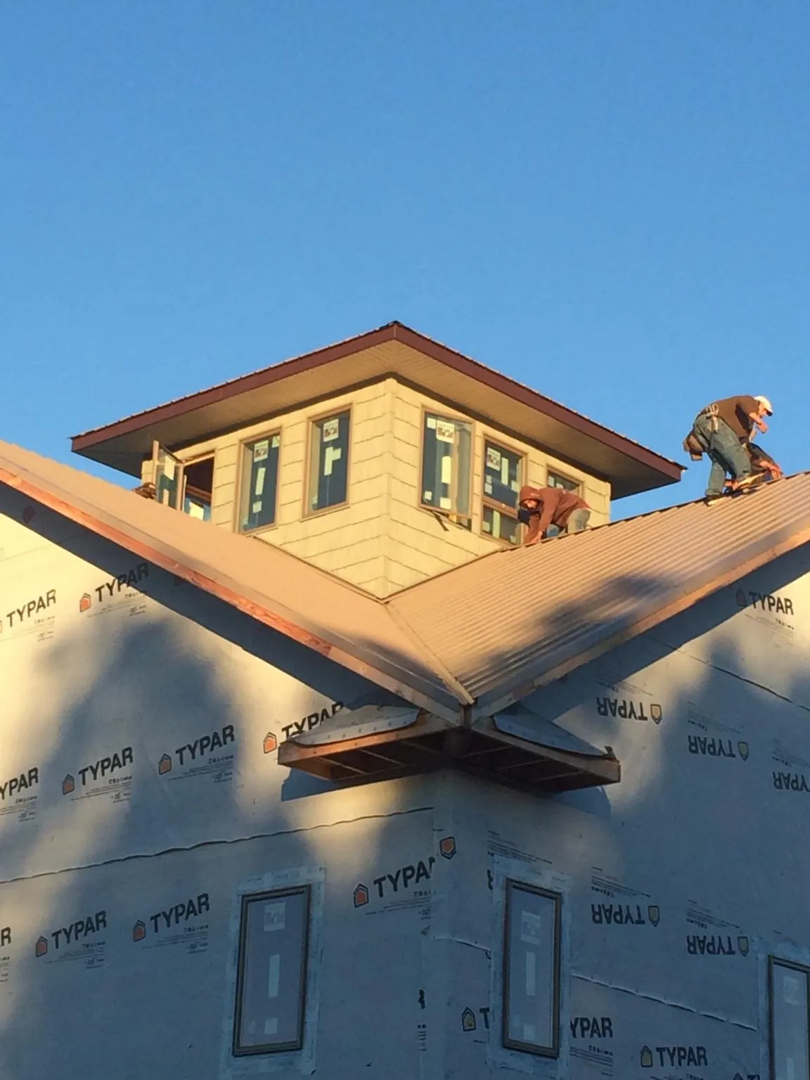 Roofers working around a rooftop cupola on a new metal roof at sunset — Roof Waterproofing in Upper Darby by Roofing Brothers